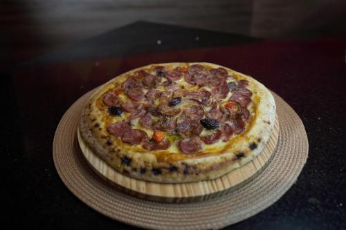 a pizza sitting on top of a plate on a table at Oasis Motel in Piracicaba