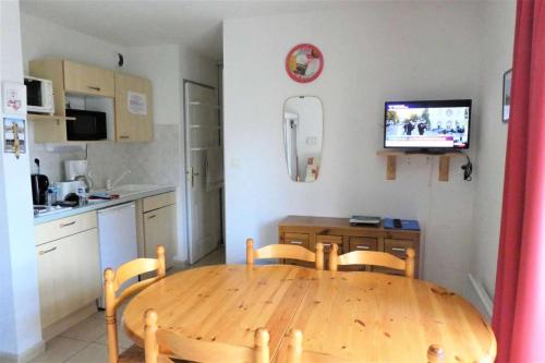 Il comprend une cuisine avec une table en bois, des chaises et une télévision. dans l'établissement Résidence Gardette - Agréable T2 de 6 couchages a Réallon B17 MAE-8511, à Réallon