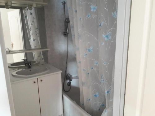 La salle de bains est pourvue d'un lavabo et d'un rideau de douche avec des fleurs bleues. dans l'établissement Résidence Gardette - Joli T2 Cosy de 6 couchages a Réallon A24 MAE-8561, à Réallon