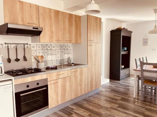 une cuisine avec des armoires en bois et un four à plaques de cuisson dans l'établissement Les Oyats locations, logement Cordouan, aux Mathes