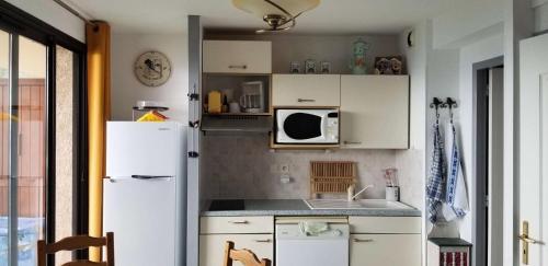 La cuisine est équipée d'un réfrigérateur blanc et d'un four micro-ondes. dans l'établissement Résidence Chabrieres - Ravissant appartement pour 6 personnes à Réallon CHAB19 MAE-8761, à Réallon