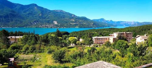 une ville avec un lac et des montagnes en arrière-plan dans l'établissement Résidence Relais - Appartement 6 couchages vue montagne à Réallon 126R MAE-8961, à Réallon