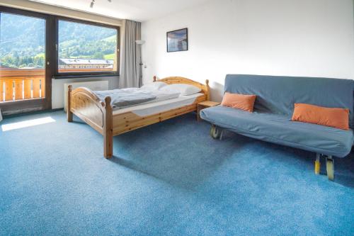 een slaapkamer met een bed, een bank en een raam bij Alan Apartment in Kaprun - free SOMMER CARD - Top of Salzburg in Kaprun