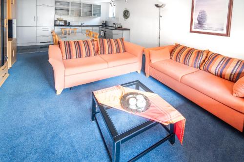een woonkamer met 2 oranje banken en een tafel bij Alan Apartment in Kaprun - free SOMMER CARD - Top of Salzburg in Kaprun
