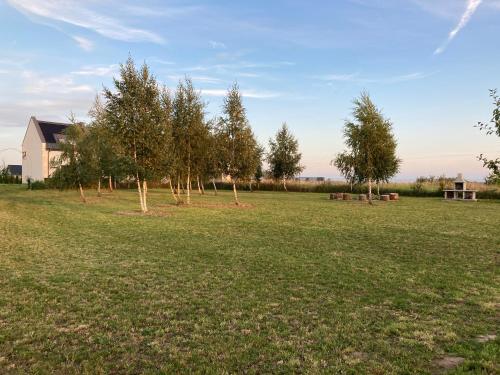 a group of trees in a field with a house at Domki Ostoja - nad Bałtykiem - cisza i piękno natury in Zastań