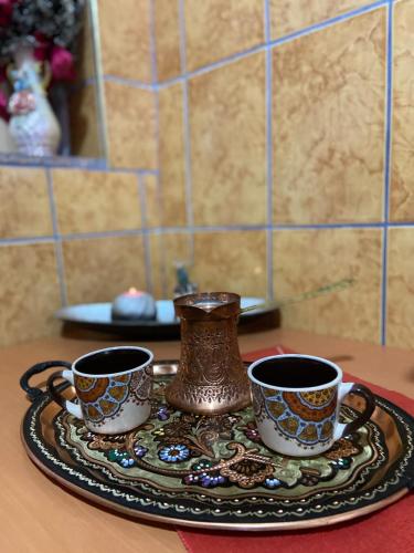 a tray with three cups and a vase on a table at Stan na dan Kaan in Sarajevo