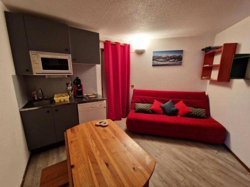 un salon avec un canapé rouge et une table en bois dans l'établissement Résidence Edelweiss - Joli appartement T2 à RISOUL à quelques mètres des pistes de ski MAE-7101, à Risoul