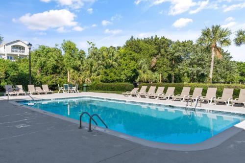 a swimming pool with lounge chairs and a house at Shipwatch #114 in East End
