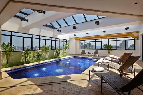 a swimming pool in a house with a glass ceiling at Transamerica Classic Higienópolis in Sao Paulo