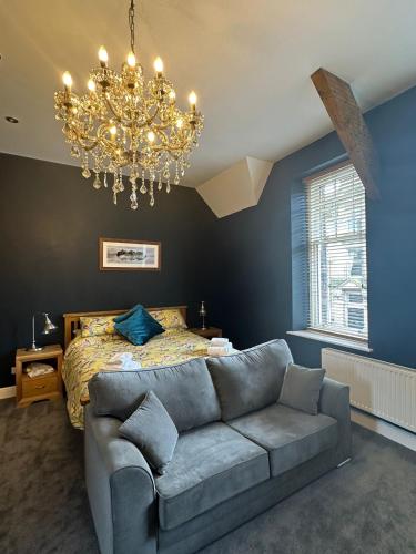a bedroom with a couch and a bed with a chandelier at Cumberland House in Cockermouth
