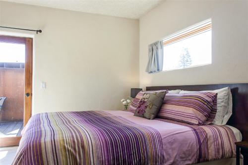 a bedroom with a bed with a purple comforter and a window at Bluebird Day - Casa Sol in Bend