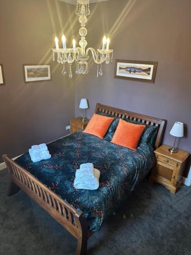 a bedroom with a bed with orange pillows and a chandelier at Cumberland House in Cockermouth