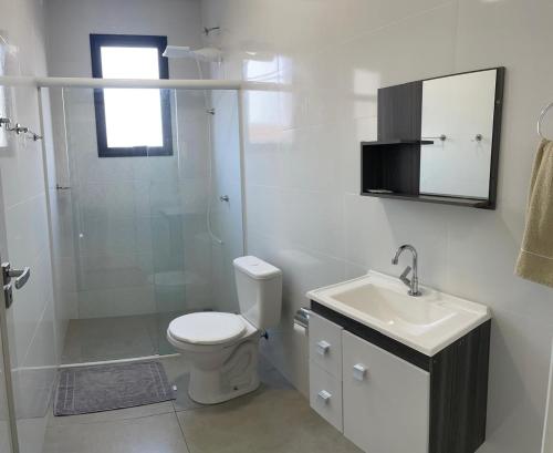 um banheiro com vaso sanitário, chuveiro e pia em Apartamento Novo Próximo a pontos turisticos em Foz do Iguaçu