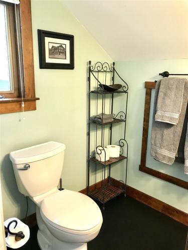 a bathroom with a toilet and a shelf with towels at Bluebird Day - Cinder Cone Bungalow in Bend