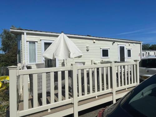 a white house with a fence and an umbrella at Rockley Valley TV36 in Lytchett Minster
