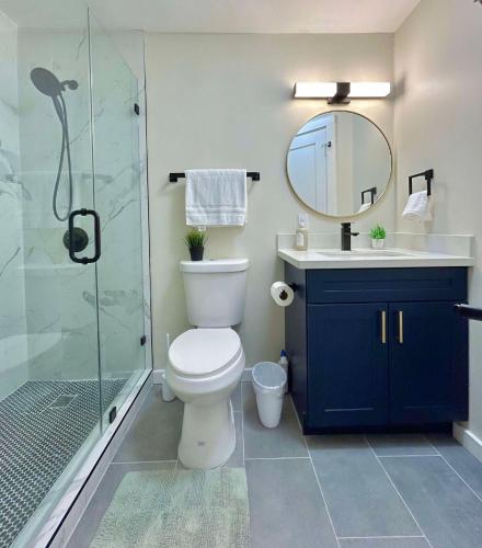 a bathroom with a toilet and a shower with a mirror at Modern Deluxe Kitchen, King Bed, Laundry, DT Renton close to Valley Med & SeaTac in Renton