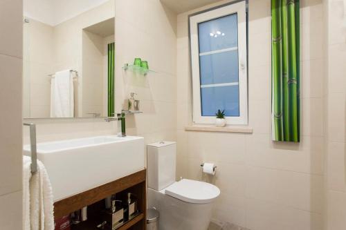 baño con aseo y lavabo y ventana en Charming Apartment in Alfama, en Lisboa