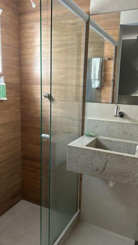 a shower with a glass door next to a sink at Hotel Petit Village Icaraí in Niterói