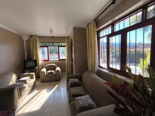 a living room with a couch and a tv and windows at Casa Waraq in Huaraz