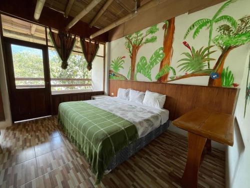 a bedroom with a bed with a painting on the wall at Biohostal Mindo Cloud Forest in Mindo