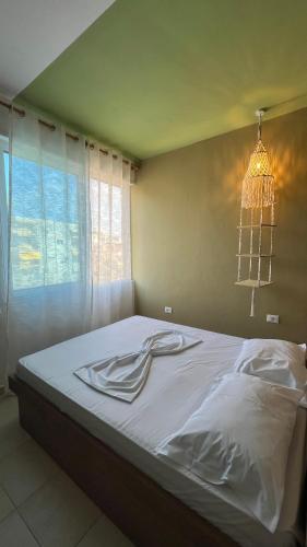 una camera da letto con un letto con lenzuola bianche e un lampadario di Kozy Studio Apartment a Durrës