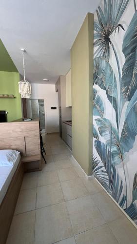 una camera da letto con un murale di una palma sul muro di Kozy Studio Apartment a Durrës