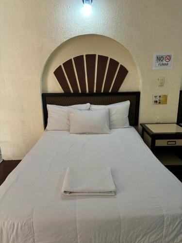 a large white bed with a white towel on it at Hotel Narváez Dorado Centro de Convenciones in Tuxtla Gutiérrez