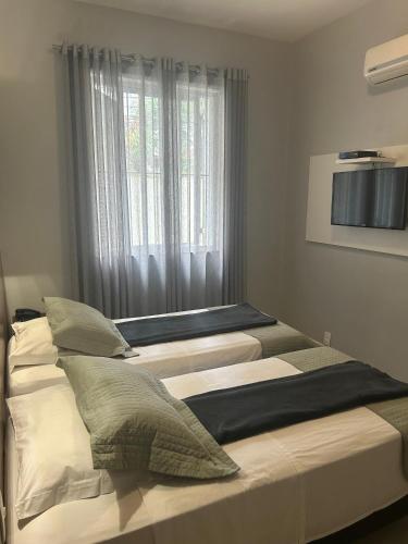 two beds in a room with a window at Hotel Petit Village Icaraí in Niterói