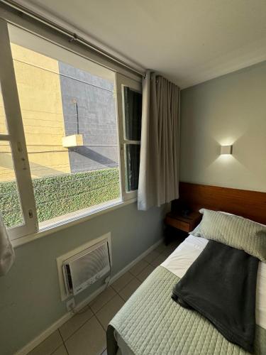 a bedroom with a bed and a window at Hotel Petit Village Icaraí in Niterói