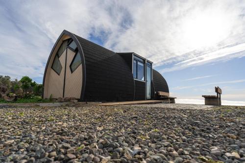 a black and white house on a rocky beach at Roca Cuadrada Lodge in Navidad