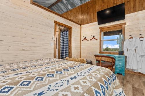 ein Schlafzimmer mit Bett, Schreibtisch und Fenster in der Unterkunft Rockin' R - Shooting Star Cabin in Fredericksburg