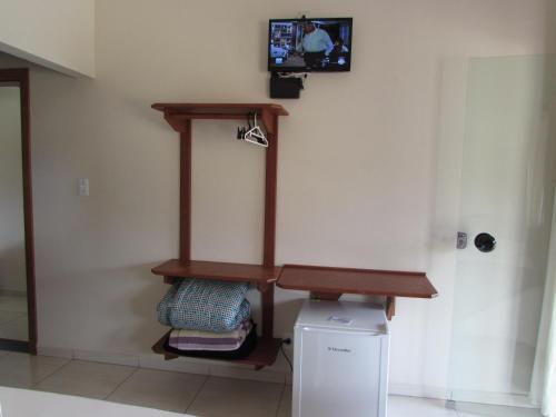 a room with a tv on a wall with a shelf at Pousada Canto Do Aconchego in Carrancas