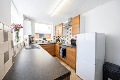 a kitchen with a white refrigerator and wooden cabinets at Manor Terrace Retreat in Accrington