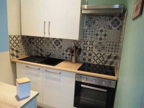 une cuisine avec des armoires blanches et un four à plaques de cuisson dans l'établissement Appartement Mont-dore centre 6-8 personnes 2 ch, à Le Mont-Dore