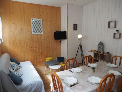 une salle à manger avec une table, des chaises et une télévision dans l'établissement Appartement Mont-dore centre 6-8 personnes 2 ch, à Le Mont-Dore