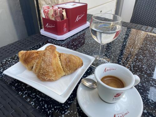 a cup of coffee and a croissant and a glass of water at Suite san Giorgio in Gravina in Puglia