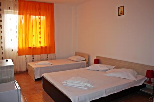 two beds in a room with an orange curtain at Vila Bucura 19 in Venus