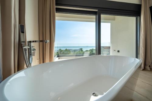 a white tub in a bathroom with a large window at Villa Mia with Heated Pool in Maslenica