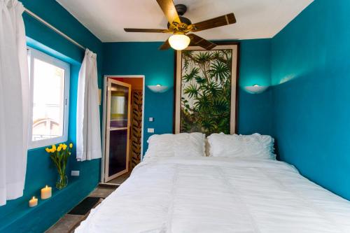 
a bedroom with a white bed and a blue wall at Garlands Del Rio in Puerto Vallarta
