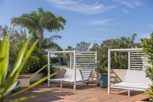 a pair of white chairs sitting on a patio at Waves Byron Bay in Byron Bay