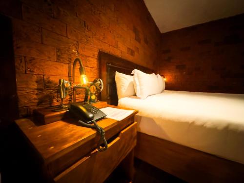 a bedroom with a bed and a phone on a table at Le Suisse Spa in Santa Lucía Milpas Altas