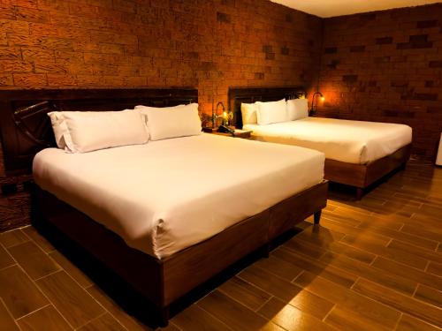 a room with two beds in a room with brick walls at Le Suisse Spa in Santa Lucía Milpas Altas