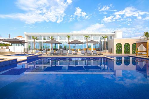 a pool with chairs and umbrellas next to a building at Bellafer Collection Hotel & Resort in Rosarito