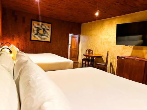 a bedroom with two beds and a flat screen tv at Le Suisse Spa in Santa Lucía Milpas Altas