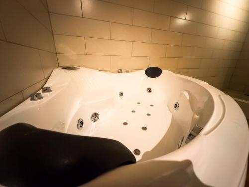 a white bath tub in a bathroom with a black seat at Le Suisse Spa in Santa Lucía Milpas Altas