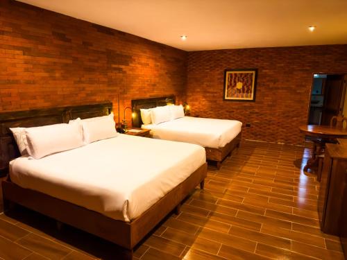a bedroom with two beds and a brick wall at Le Suisse Spa in Santa Lucía Milpas Altas