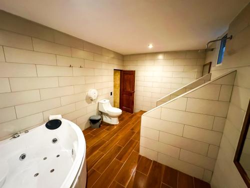 a bathroom with a tub and a toilet in it at Le Suisse Spa in Santa Lucía Milpas Altas