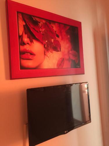 a television on a wall with a picture of a woman at Holiday Home Gionny & Mary in Taormina