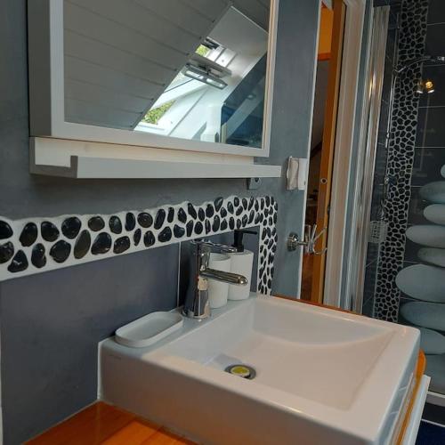 une salle de bain avec un lavabo blanc et un miroir dans l'établissement Penty typique Kercab dans un ancien moulin, à Plomodiern