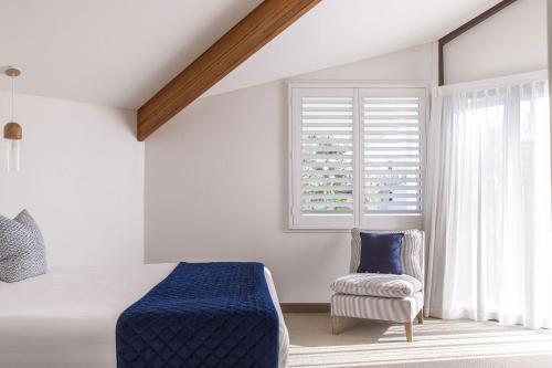 a bedroom with a bed and a chair and a window at Waves Byron Bay in Byron Bay